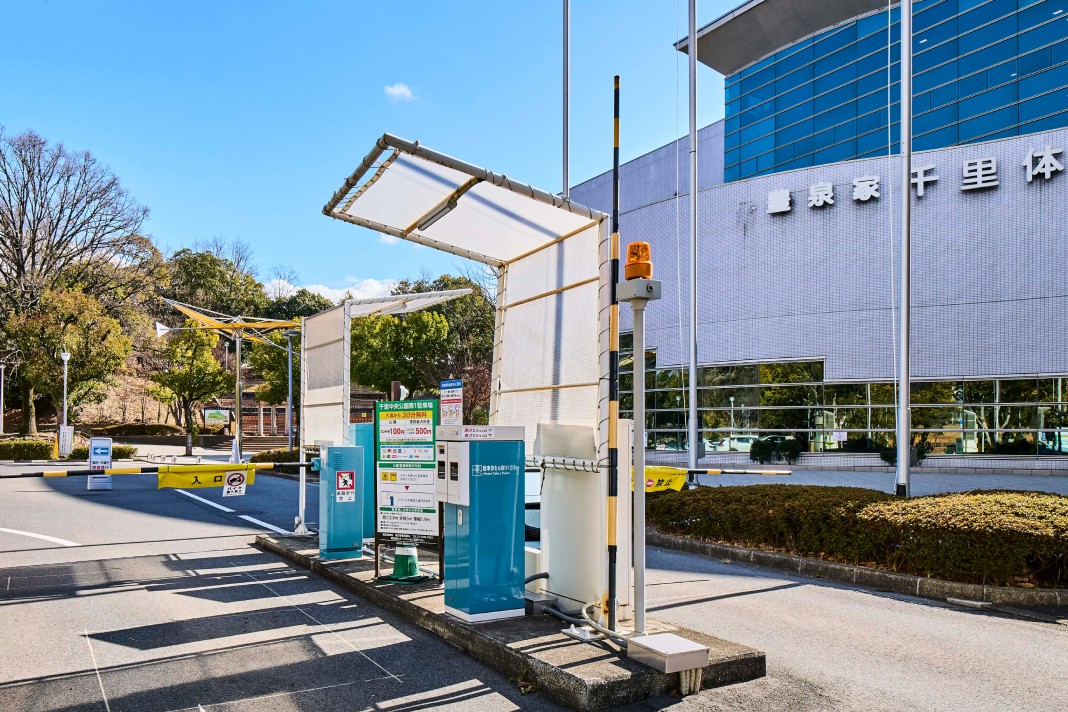 スムーズな車両誘導と管理を実現するために設置された、発券機、精算機、黄色いゲートバーなどの駐車場設備一式