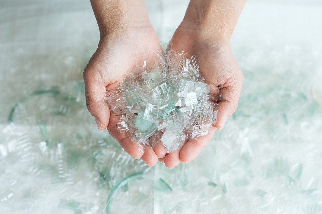 破砕処理によってフレーク状になった、きれいで透明なプラスチックチップを両手で掬い上げている様子