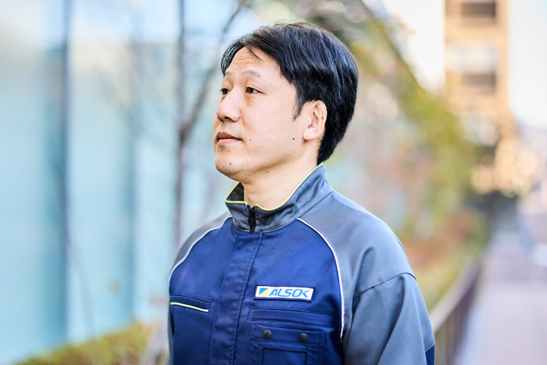 胸元にALSOKのロゴが入った制服を着用している男性スタッフの横顔